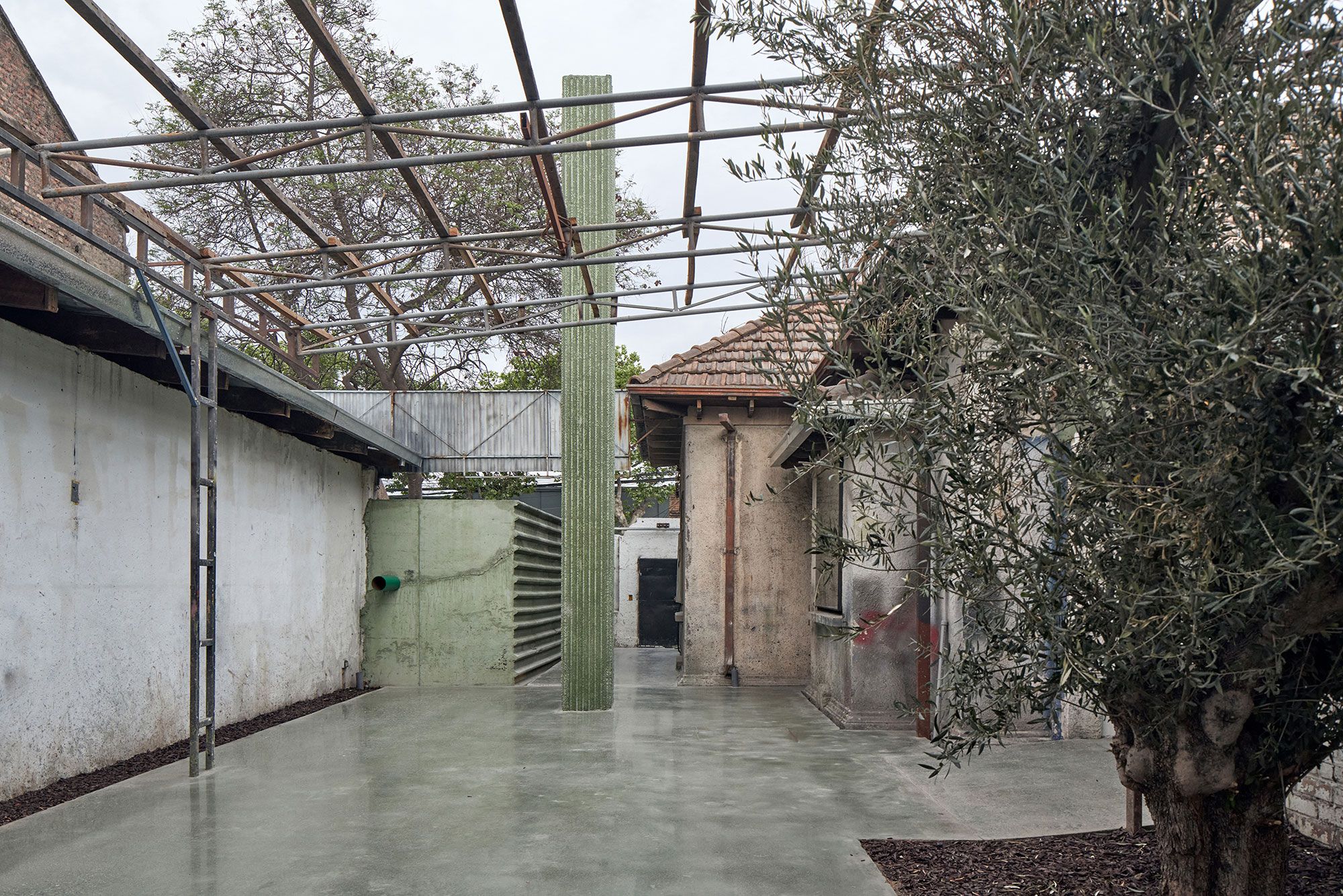 El pilar verde, entre la casa original y el olivo.